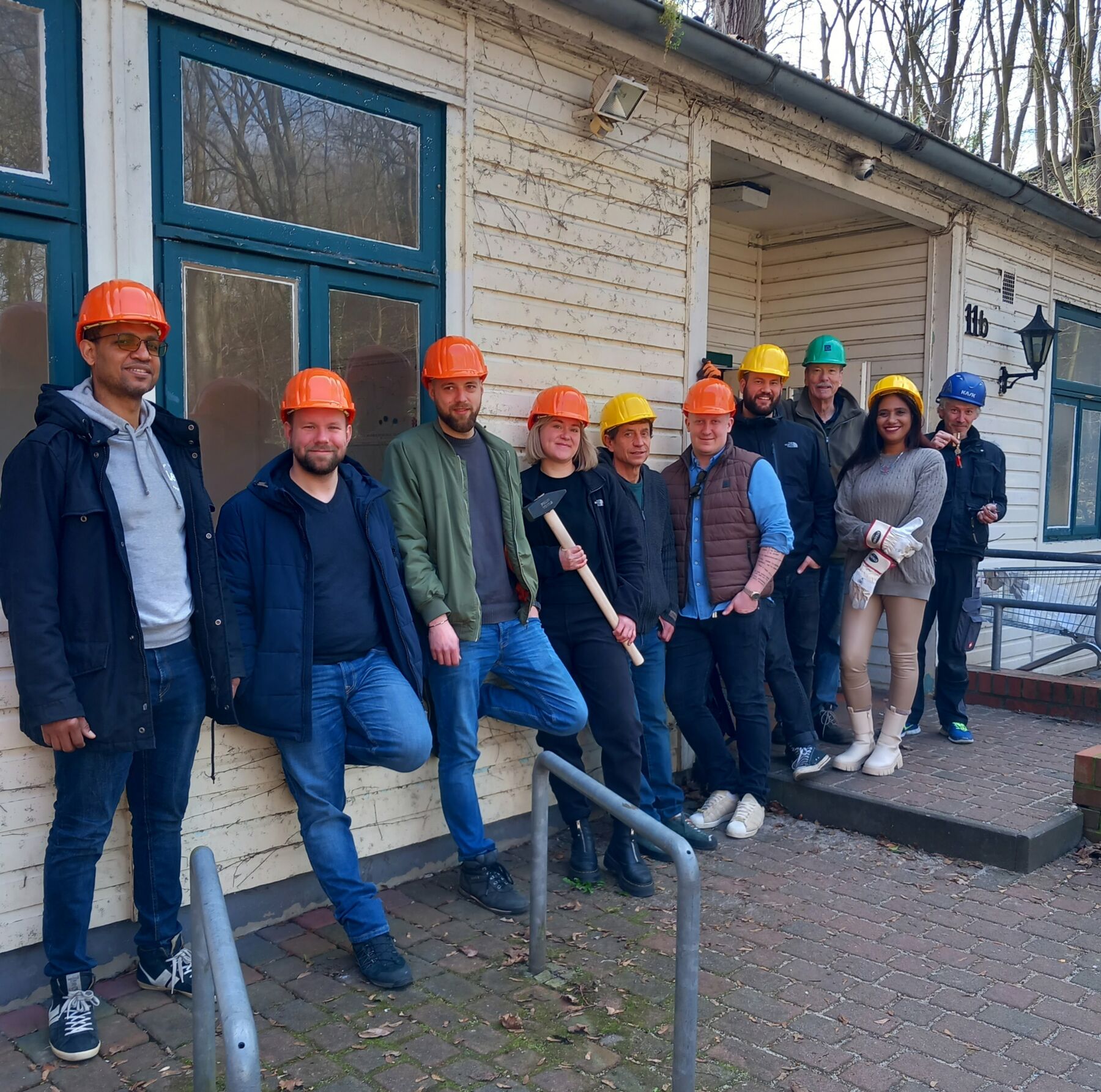 Gruppe von Mitarbeitenden der HERBERGE.plus vor dem baufälligen Hinterhaus